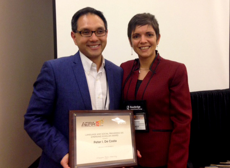 man with brown hair and glasses holding award poses with woman with brown hair